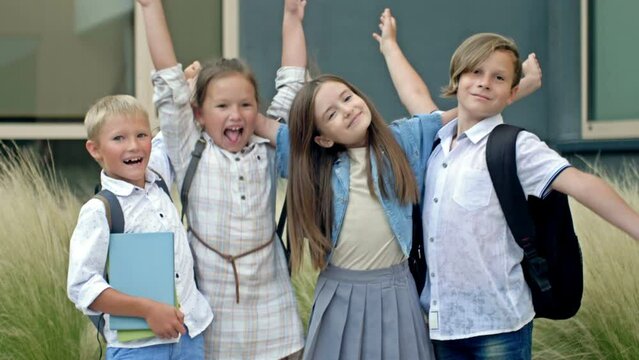 Four friends, elementary school students, stand in an embrace in the schoolyard. Classmates. School friendship.