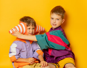 Two kids in 80s stylish clothes play on yellow background