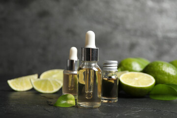 Obraz na płótnie Canvas Lime essential oil and cut citrus fruits on black table