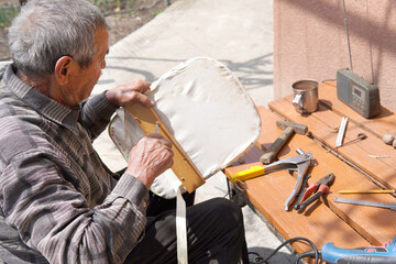Old man fixing broken chair