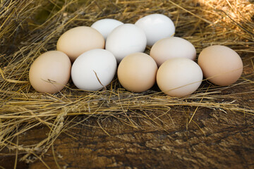 Fresh raw eggs and straw on wooden surface