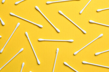 Many cotton buds on yellow background, flat lay