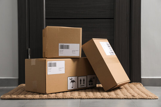 Cardboard boxes on floor mat near entrance. Parcel delivery service