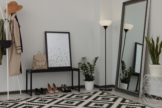 Stylish hallway room interior with bench, shoes, clothes rack and floor mirror