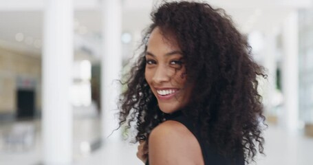 Business woman walking, looking back and smiling into a modern office. Confident female businessperson with style at work. Business professional with big smile arriving at work in the morning.