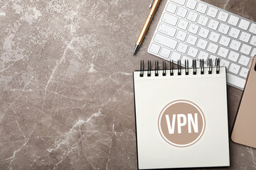 Notebook with acronym VPN and space for text on brown marble table, flat lay. Secure network connection