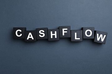 Black wooden cubes with phrase Cash FLow on grey background, flat lay