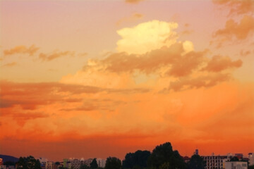 Fototapeta premium Beautiful orange sky with clouds over city at sunset