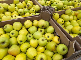 Ripe yellow-green apples in cardboard boxes are sold at the farmer's market.