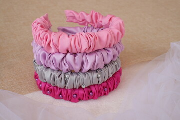 Soft pastel color handmade scrunchy or scrunchies headband made out of satin silk fabric texture. A hairband or headpiece with ruffle pattern.