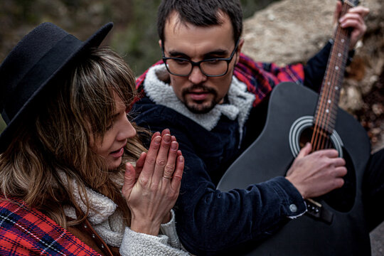  couple in love walking in the countryside road against the mountain and road, man holding the guitar, people hitchhiking . A man gently hugs a woman