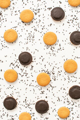 Contrast pattern made with chocolate cookies and chocolate sprinkles on white background. Chaotic flat lay. Process of making birthday cheesecake.