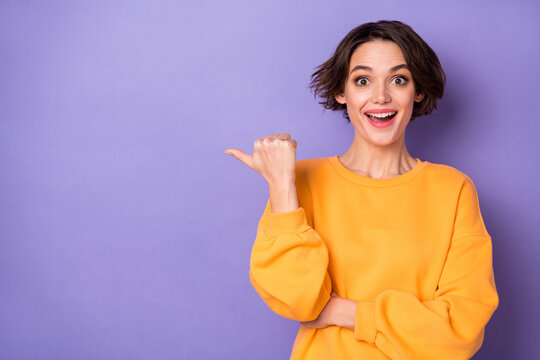 Photo of excited positive lady indicate thumb finger empty space blank ad isolated on violet color background