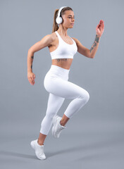 Young fitness woman runner with headphone run, isolated on gray background. Dynamic movement.