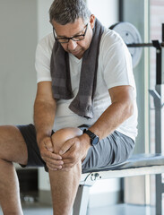 Naklejka premium Active senior in gym with knee injury