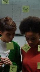 A woman is drawing a business strategy on a glass board working with assistant