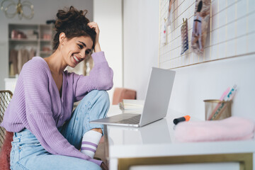 Young millennial woman freelancer work remote at home sitting at table with laptop computer device. Female student learning online with webinar course while using portable netbook for distantly study