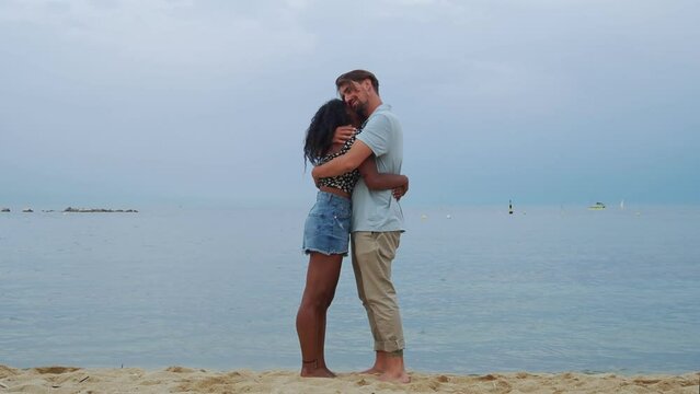 Young Diverse Heterosexual Couple Lovingly Embracing On The Beach During A Sunset. Lovers, Honeymoon