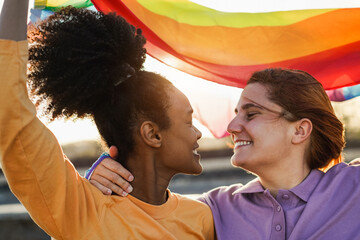 Happy women gay couple holding rainbow flag outdoor - Love and lesbian concept