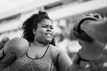 Deurstickers African curvy woman and personal trainer doing boxing workout session outdoor - Focus on face - Black and white editing © DisobeyArt