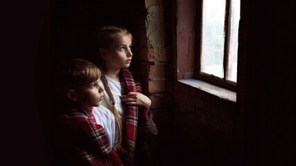 Children stand at the window - obrazy, fototapety, plakaty