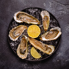 Opened fresh oysters on a plate, served with lemon and ice.