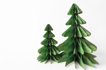 Fototapeta na wymiar Handmade foldable Christmas trees from plastic free material - green paper isolated on white background. DIY concept.