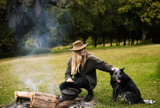 Woman making food on the camp fire with her dog