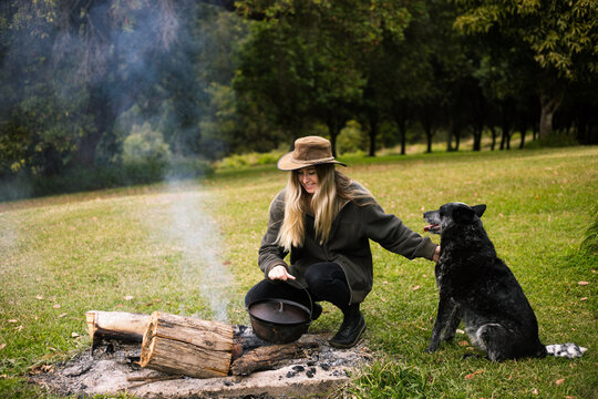 Woman making food on the camp fire with her dog