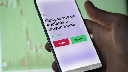 Un investisseur analyse un fonds etf obligations de sociétés à moyen terme sur un graphique. Un téléphone affiche le cours de l'ETF. Texte en français francais Obligations de sociétés à moyen terme
