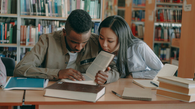 diligent biracial students preparing for exams doing homework in college library