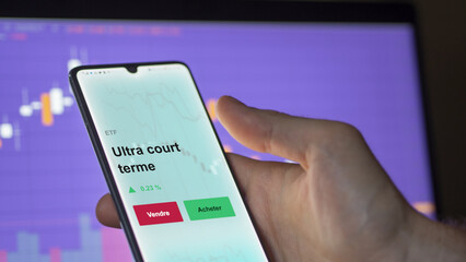 Un investisseur analyse un fonds etf ultra court terme sur un graphique. Un téléphone affiche le cours de l'ETF. Texte en français francais Ultra court terme