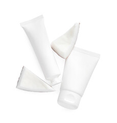 Tubes of hand cream and coconut pieces on white background, top view