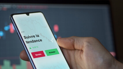 Un investisseur analyse un fonds etf suivre la tendance sur un graphique. Un téléphone affiche le cours de l'ETF. Texte en français francais suivre la tendance