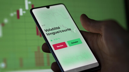Un investisseur analyse un fonds etf volatilité longue/courte sur un graphique. Un téléphone affiche le cours de l'ETF. Texte en français francais Volatilité longue/courte