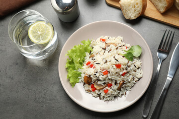 Delicious rice pilaf with mushrooms served on grey table, flat lay