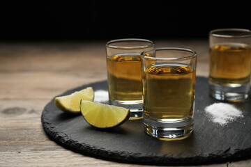 Mexican Tequila shots, lime slices and salt on wooden table