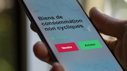 Un investisseur analyse un fonds etf biens de consommation non cycliques sur un graphique. Un téléphone affiche le cours de l'ETF. Texte en français francais Biens de consommation non cycliques