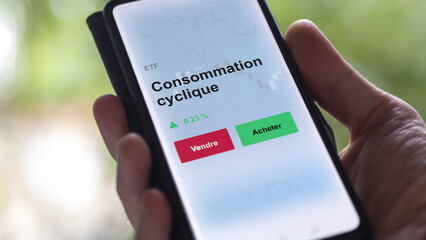 Un investisseur analyse un fonds etf consommation cyclique sur un graphique. Un téléphone affiche le cours de l'ETF. Texte en français francais Consommation cyclique