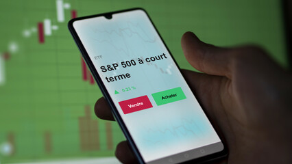 Un investisseur analyse un fonds etf s&p 500 à court terme sur un graphique. Un téléphone affiche le cours de l'ETF. Texte en français francais S&P 500 à court terme