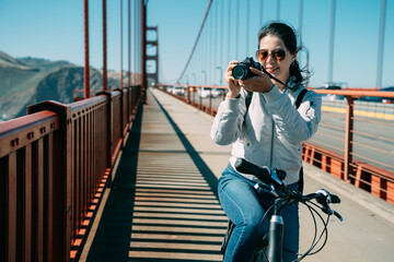 portrait Asian female tourist wearing sunglasses is shooting a photo with a digital camera in the...