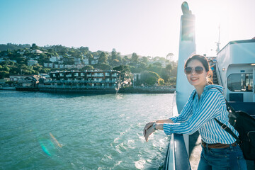 happy asian woman wearing sunglasses is enjoying the beautiful seascape on a ferry boat with hands...