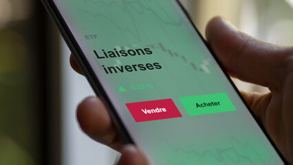 Un investisseur analyse un fonds etf liaisons inverses sur un graphique. Un téléphone affiche le cours de l'ETF. Texte en français francais liaisons inverses