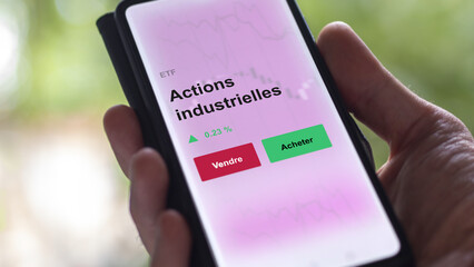 Un investisseur analyse un fonds etf actions industrielles sur un graphique. Un téléphone affiche le cours de l'ETF. Texte en français francais Actions industrielles