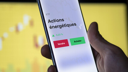 Un investisseur analyse un fonds etf actions énergétiques sur un graphique. Un téléphone affiche le cours de l'ETF. Texte en français francais.