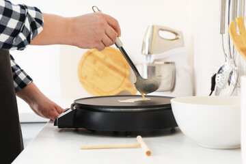 Man cooking delicious crepe on electric pancake maker in kitchen, closeup