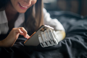 Girl disability bionic arm using phone, reading social media and chatting in bed, disabled cyborg...