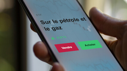 Un investisseur analyse un fonds etf sur le pétrole et le gaz sur un graphique. Un téléphone affiche le cours de l'ETF. Texte en français francais sur le pétrole et le gaz