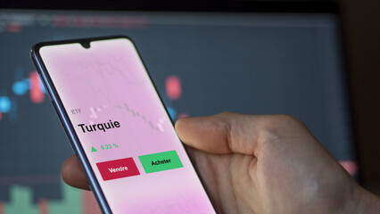 Un investisseur analyse un fonds etf turquie sur un graphique. Un téléphone affiche le cours de l'ETF. Texte en français francais Turquie