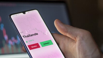 Un investisseur analyse un fonds etf thaïlande sur un graphique. Un téléphone affiche le cours de l'ETF. Texte en français francais Thaïlande
